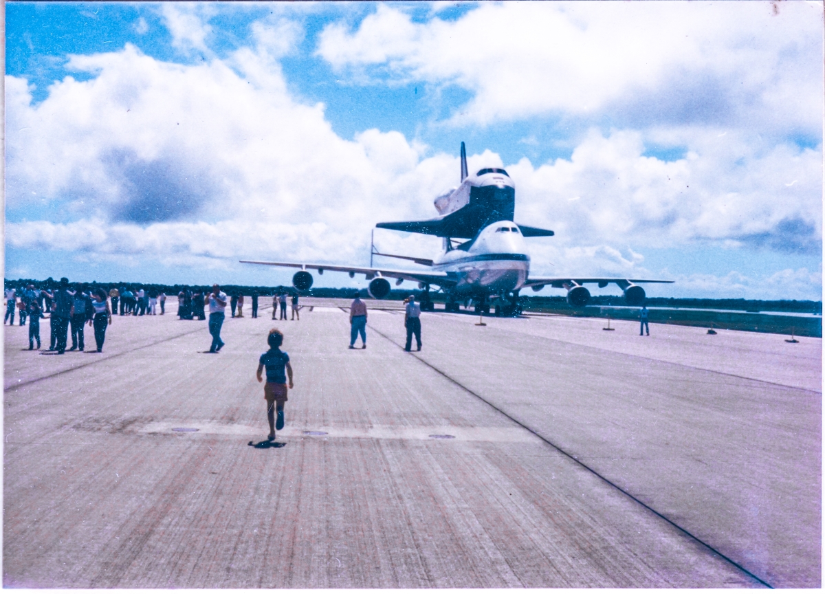 Kai MacLaren runs gleefully toward OV-101, Enterprise, perched atop its 747 Carrier Aircraft at the south end of the runway at the Shuttle Landing Facility, Kennedy Space Center, Florida, during a NASA Open House which was held in November, 1985.